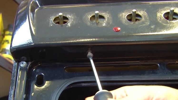 Open the grill door and use a Phillips screwdriver to remove the two screws under the control panel