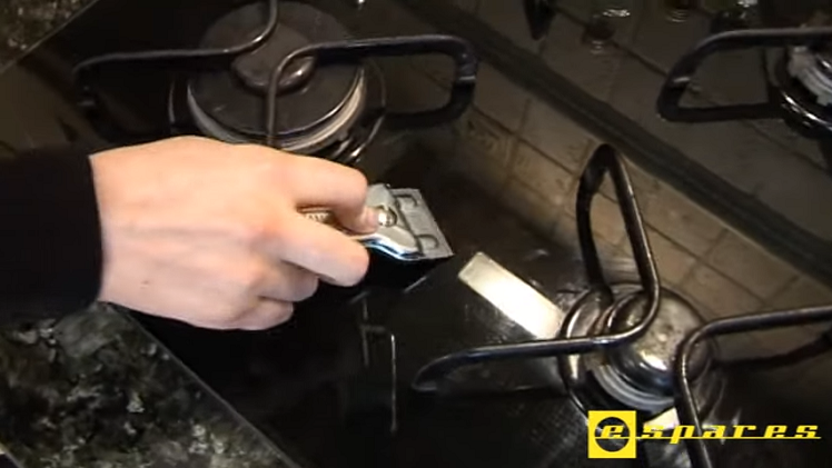 Using A Hob Scraper To Remove Burnt On Residue From The Hob Top