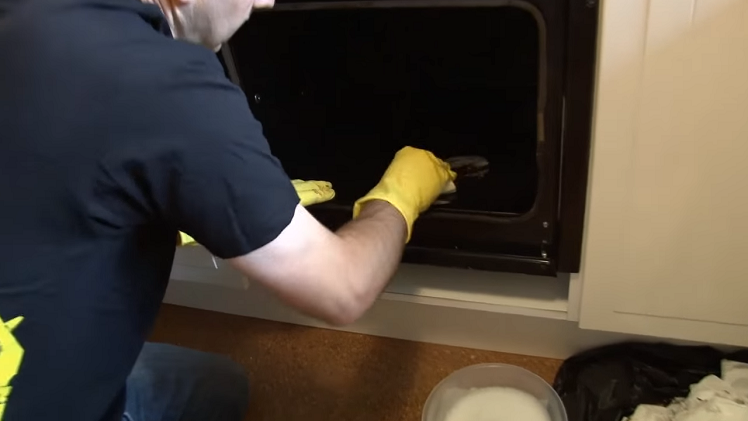 Using A Scouring Sponge And Soapy Water To Scrub Away Burnt On Residue Inside The Oven