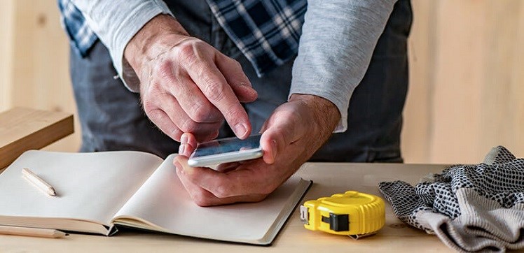 Man Watching Phone Whilst Doing DIY