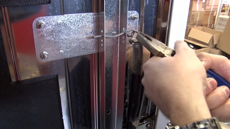 Reconnecting The Door Spring To The Hinge With A Pair Of Pliers