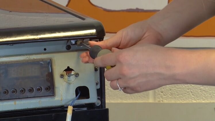 Use a Phillips screwdriver to fit the two screws to the front of the top panel