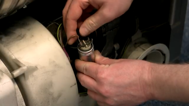 Removing The Electrical Connections Attached To The Faulty Capacitor By Gently Lifting Them Out