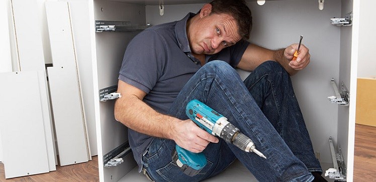 Man Holding Drill Looking Stressed Inside Flat Pack Furniture