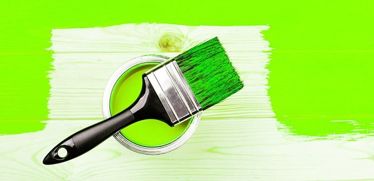 Paintbrush Resting On Green Paint Can Over Half Painted Flooring