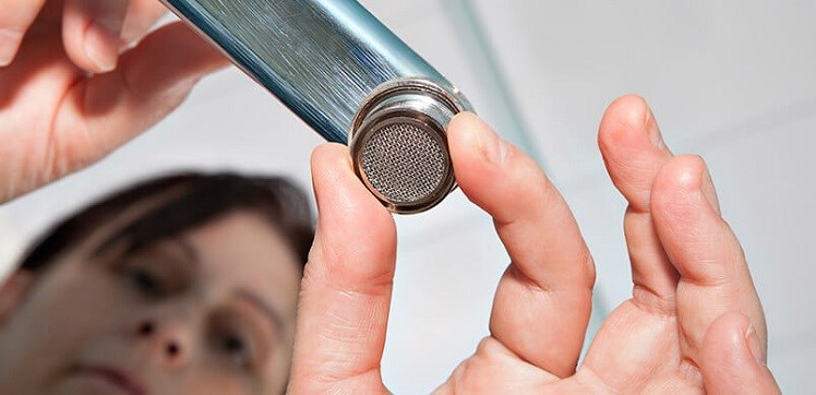 Woman Unscrewing the End of a Tap