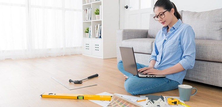 Woman Typing On A Laptop Whilst Doing DIY In Her Living Room