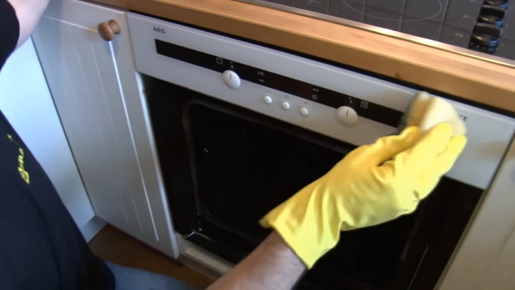 Cleaning The Oven Knobs And Fascia Panel With Cleaning Spray And Kitchen Roll