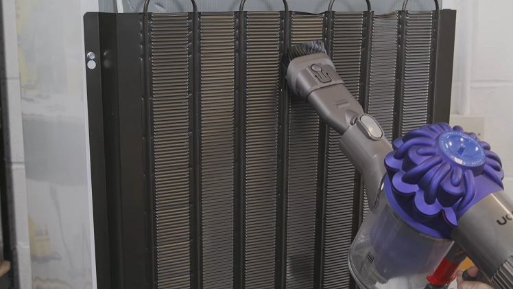Cleaning The Condenser Coils At The Back Of The Fridge Using A Vacuum Cleaner With A Brush Attachment
