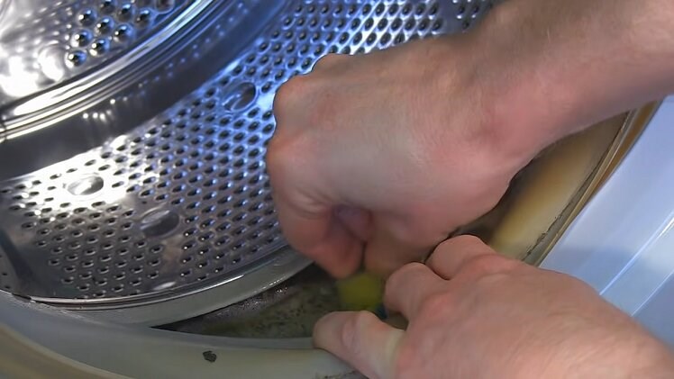Cleaning The Inside Folds Of The Washing Machine Door Seal With A Scourer