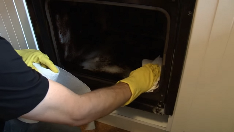 Wiping The Interior Of The Oven With A Handful Of Kitchen Roll