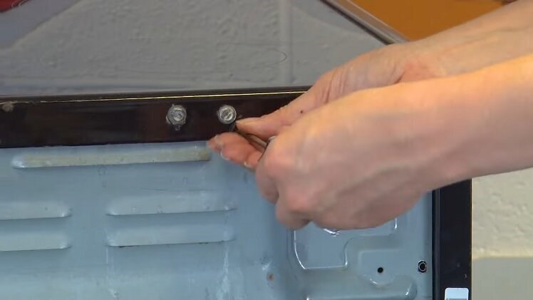 Secure the top panel by fitting the two screws at the back of the oven