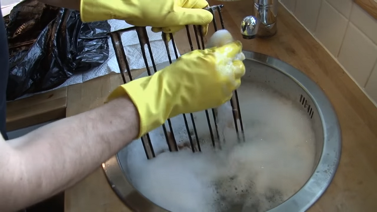 Scrubbing The Oven Shelves With A Scourer In Warm Soapy Water