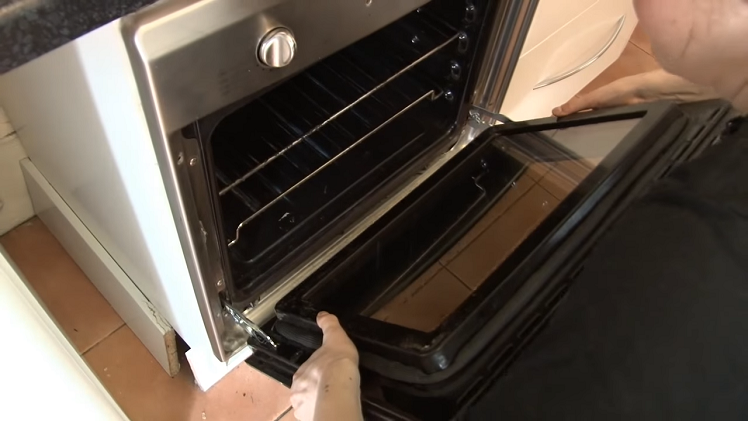 Putting The Door Back On The Oven By Slotting The Door Hinges Into The Oven