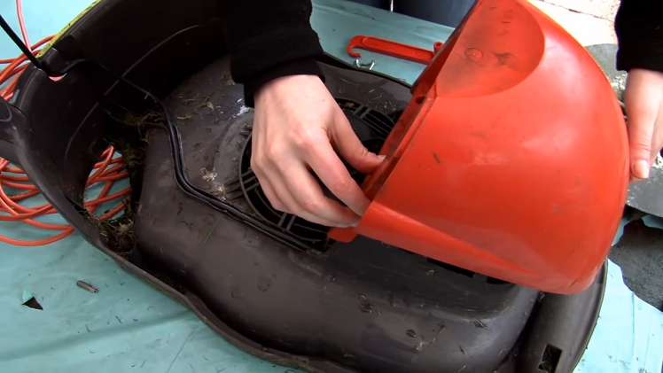 Rescrewing The Lawnmower Cover Back Into Place With Three Screws