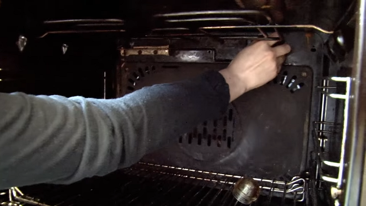 Screwing The New Bulb And Lamp Cover Into Place Inside The Back Of The Oven