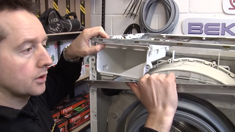 Remove the complete detergent tray by removing the metal crossbar in front of the tray if necessary.