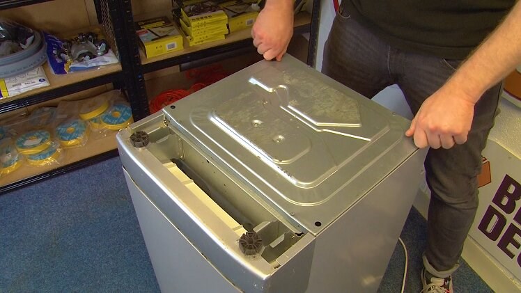 Flip the dishwasher upside down, unscrew and remove the two rear feet on the bottom panel by hand