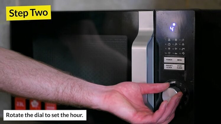 Rotating The Dial On The Sharp Microwave To Change The Hour Displayed On The Digital Clock