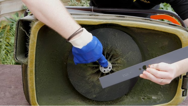 Placing The New Blade Onto The Lawnmower With The Flat Side Facing Downwards Towards The Grass