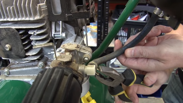 Draining The Main Fuel Reservoir On The Petrol Lawnmower By Uncoupling The Fuel Line