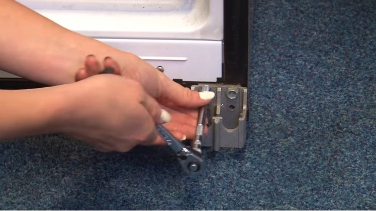 Removing The Chassis Bracket From The Fridge Bottom Hinge By Removing The Three Ten Millimeter Bolts With A Ratchet