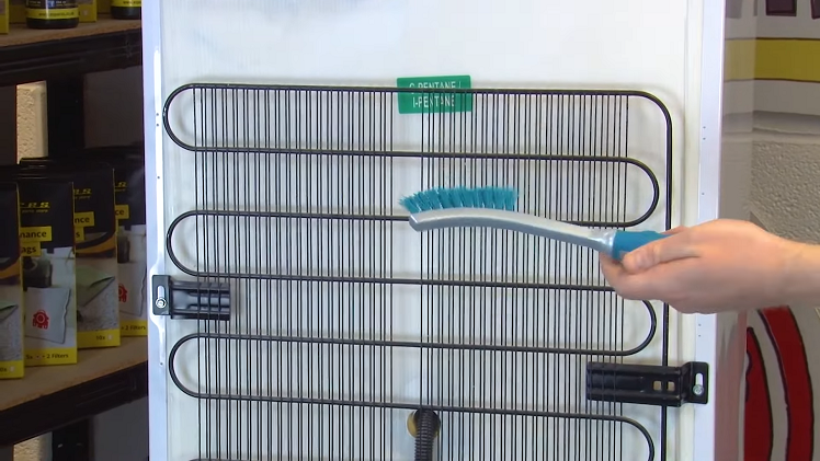 Cleaning The Condenser Coils At The Back Of The Fridge With A Brush