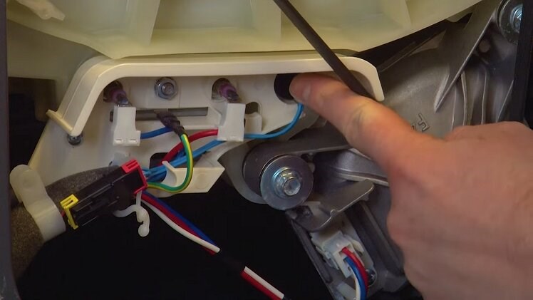 The thermostat plugged in beneath the washing machine's drum and to the right of the heating element
