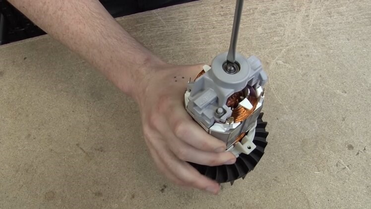 Using A Flathead Screwdriver To Tighten The Armature And Fully Secure The Transferred Parts To The Motor
