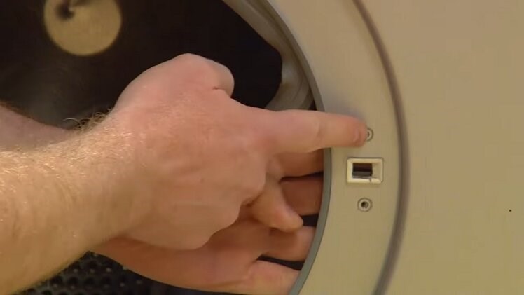 Slot the new door lock into place behind the side of the washing machine door frame