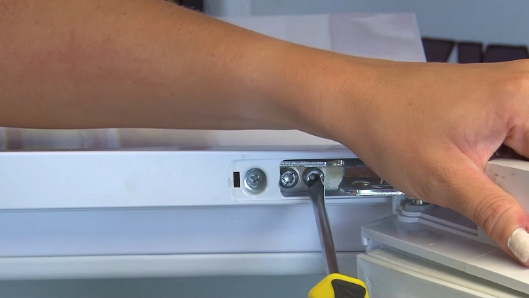 Using A Flat Blade Screwdriver To Remove The Two Hinge Screws Found Beneath The Fridge Door Hinge Cover