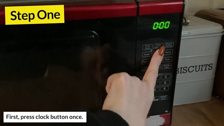 Press the 'Clock' button on the front of the microwave
