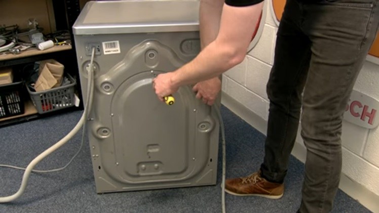 Unscrew the back panel off the washing machine