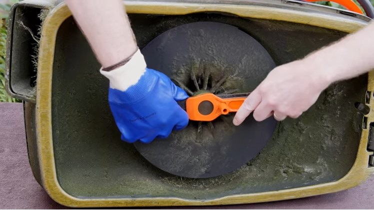 Wearing A Glove And Unscrewing The Nut That Is Holding The Blade Using A Flymo Spanner And Lifting The Blade Off