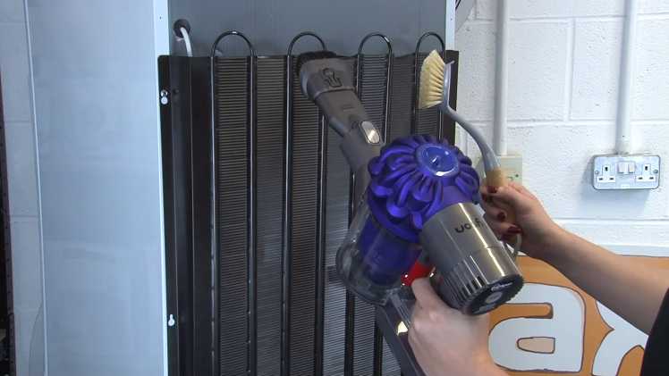 Using A Vacuum Cleaner To Clean The Condenser Coils At The Back And The Underside Of The Fridge Freezer