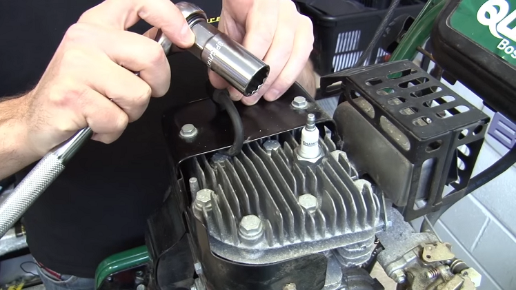 Removing A Standard Fourteen Millimeter Petrol Lawnmower Spark Plug With A Twenty One Millimeter Socket Which Is Specifically For Spark Plugs