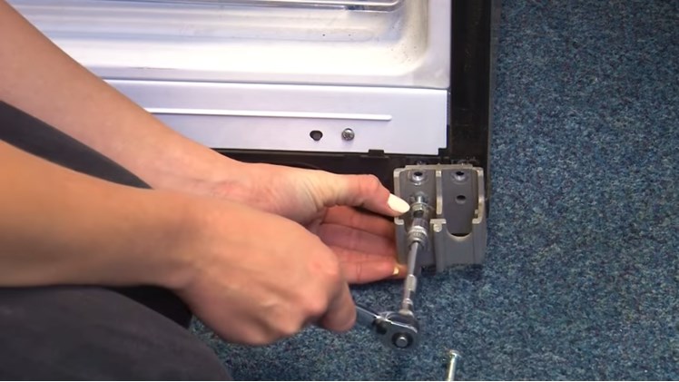 Refitting The Fridge Chassis Bracket By Refitting The Three Ten Millimeter Bolts With A Ratchet And Inserting The Lower Hinge