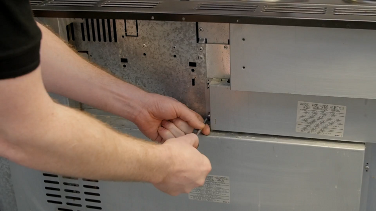 Unscrewing The Access Panel At The Back Of The Cooker
