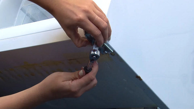 Screwing The New Fridge Freezer Bottom Hinge Into Place Using A Ratchet