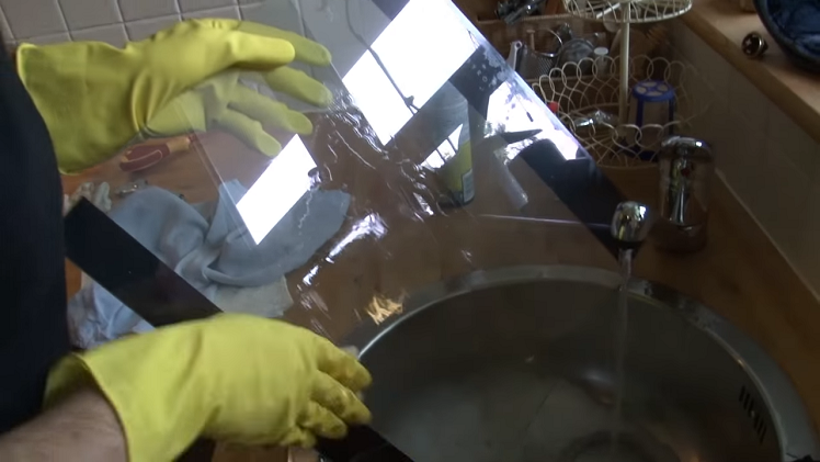 Rinsing The Door Glass Under A Tap To Remove The Kitchen Spray