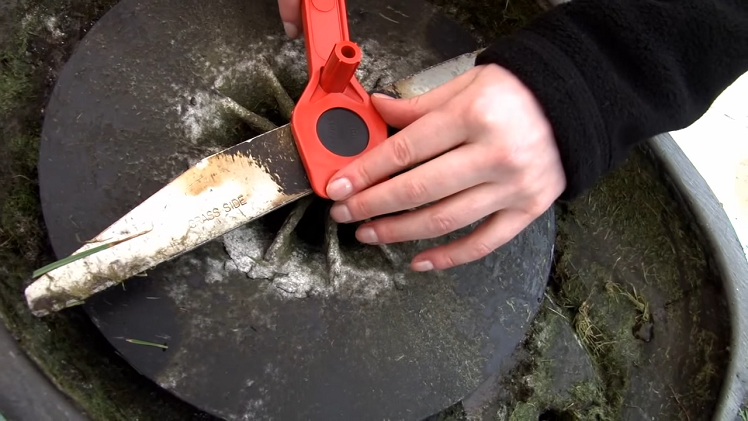 Unscrewing The Large Plastic Screw Underside The Mower That Holds The Lawnmower Blade In Place With A Flymo Spanner