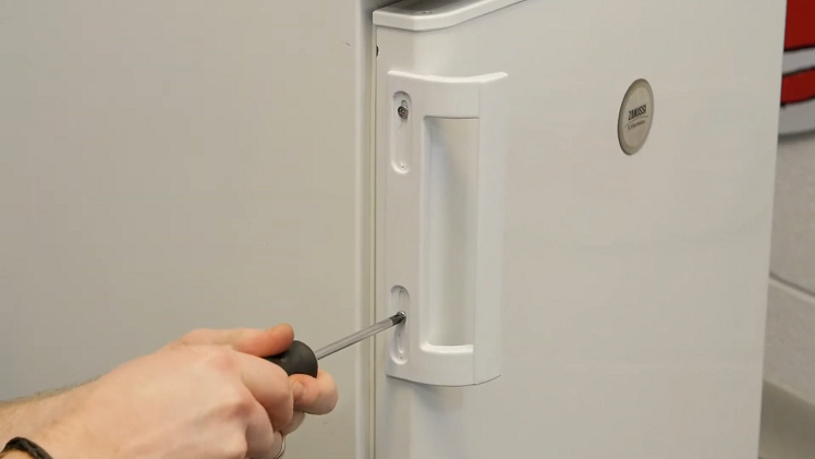 Using A Screwdriver To Secure The Door Handle Onto The Fridge Or Freezer