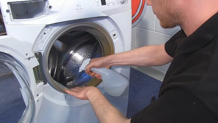 Spraying The eSpares Washing Machine Cleaner Into The Folds Of The Washing Machine Door Seal