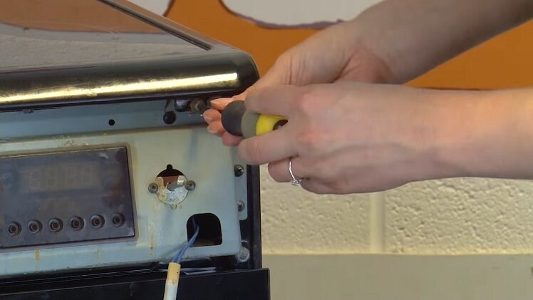 Fit the two screws to secure the top panel in place at the front of the oven