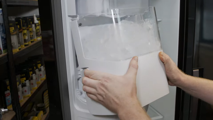 Taking Hold Of The Bucket And Pulling The Two Tabs On Either Side And Pulling The Bucket Out