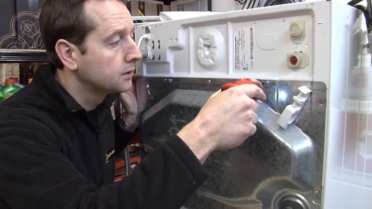 Turn the washing machine around and remove the back panel by unscrewing the screws that hold the panel in place.