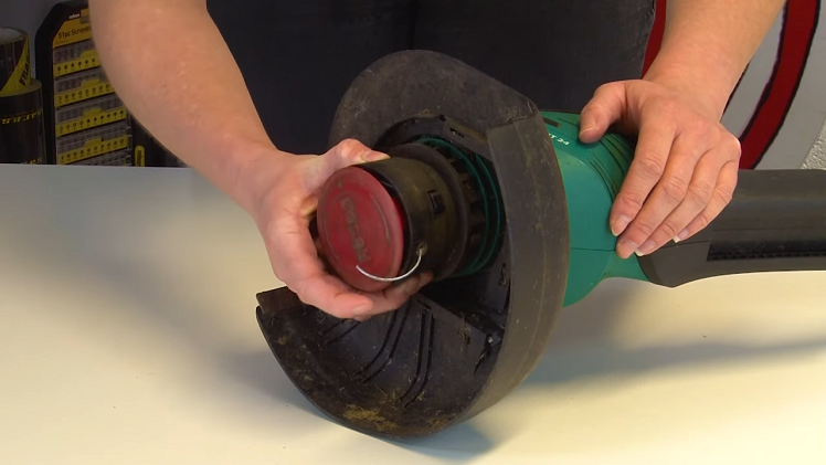 Removing The Spool Cover By Pressing The Two Tabs On Either Side Of The Trimmer Head At The Same Time